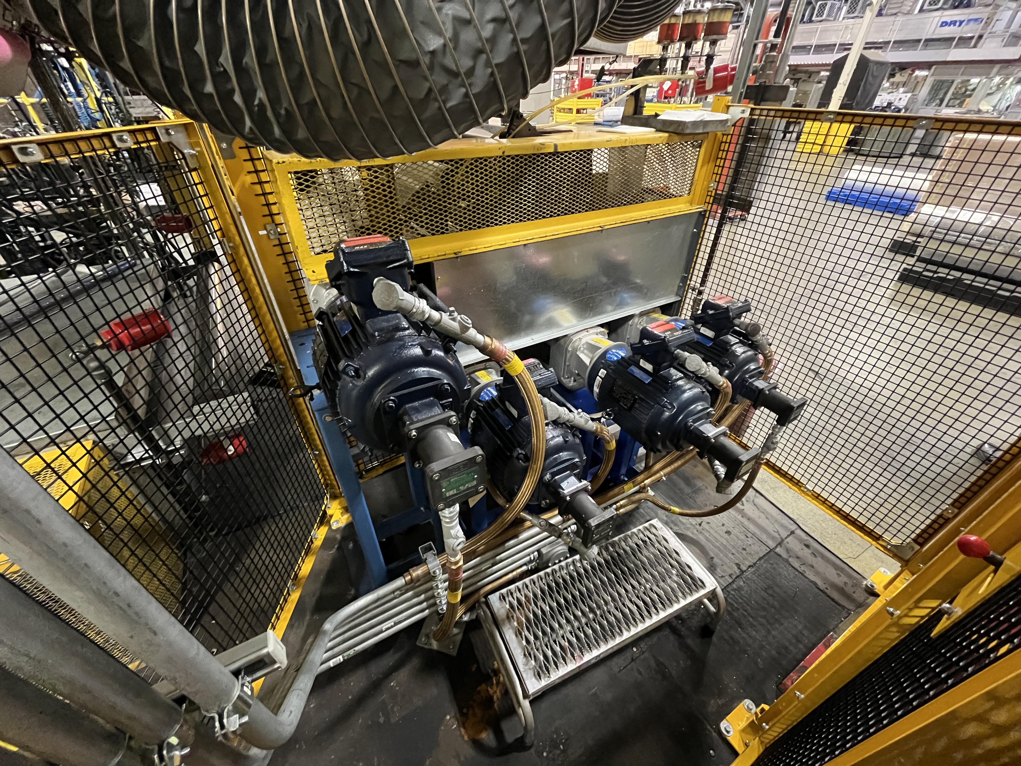 Consolidated gearing into direct-driven motors and gearboxes on custom baseplate stands, surrounded by a yellow safety fence retrofitted by Apex Industrial Automation.