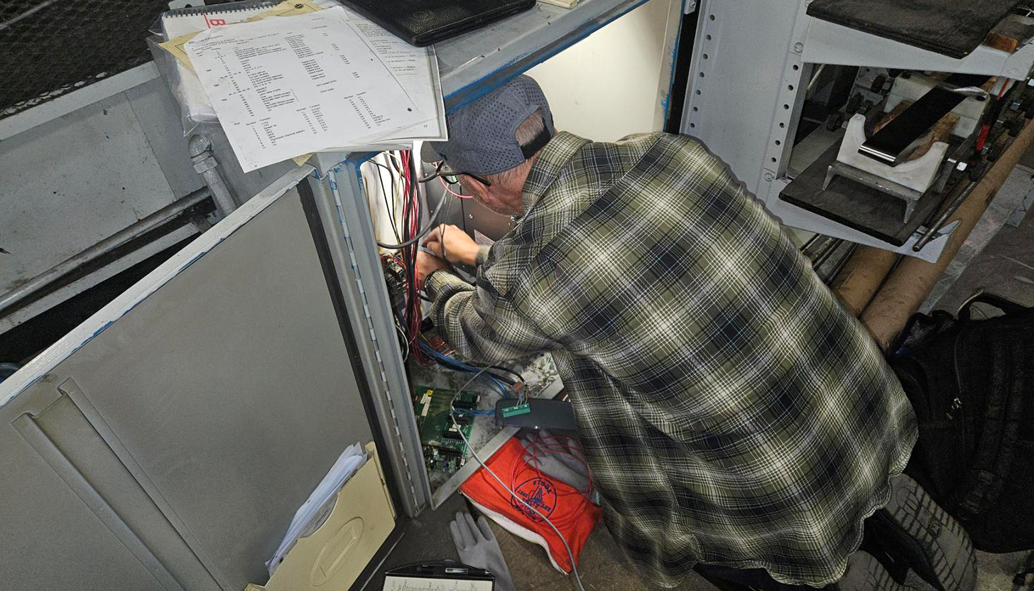 Mechanical engineer adjusting control panel during retrofitting of hose assembly manufacturing plant.