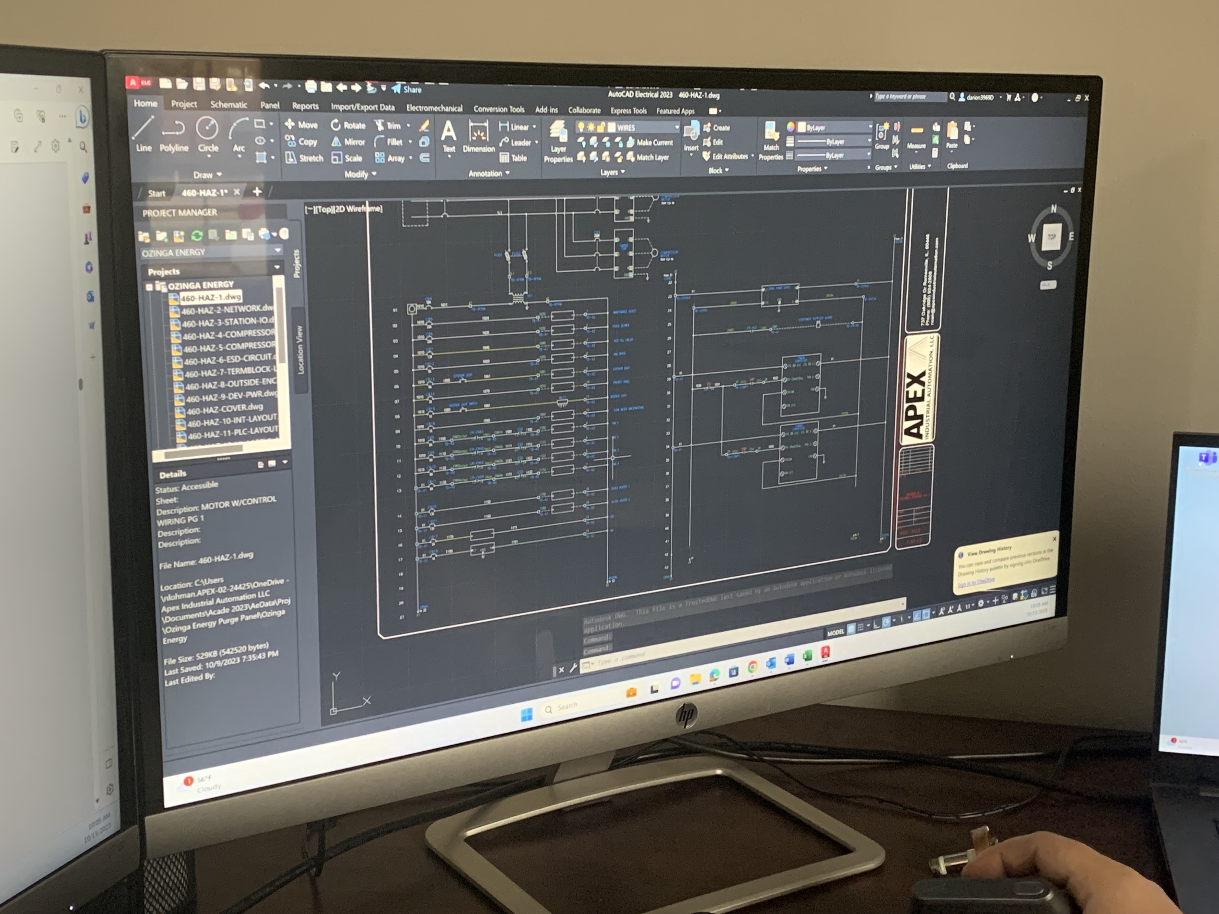 Design engineer's monitor at Apex Industrial Automation displaying an industrial control panel design in AutoCAD.