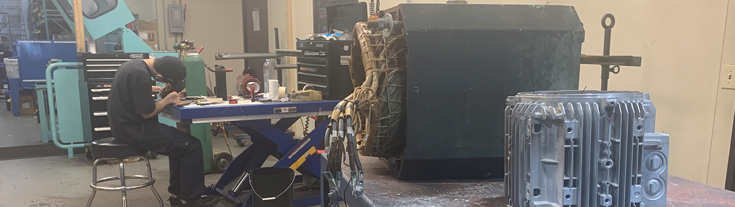 Apex Industrial Automation repair technician working on a motor in the winding room, with a disassembled motor on a lift table in the foreground.
