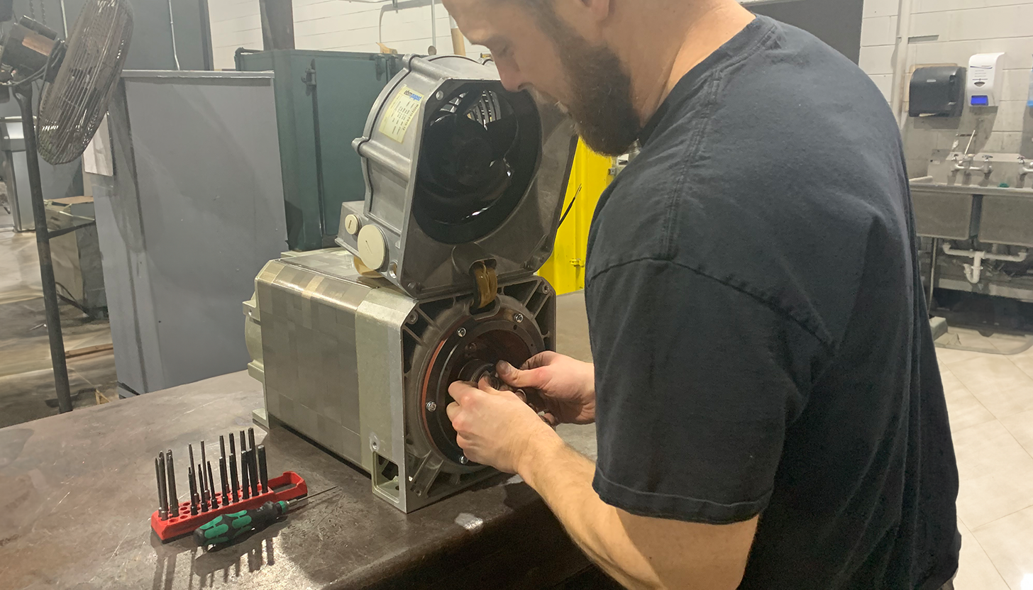 Experienced technician at Apex Industrial Automation repairing a servo motor on a well-organized workbench in the servo repair lab.
