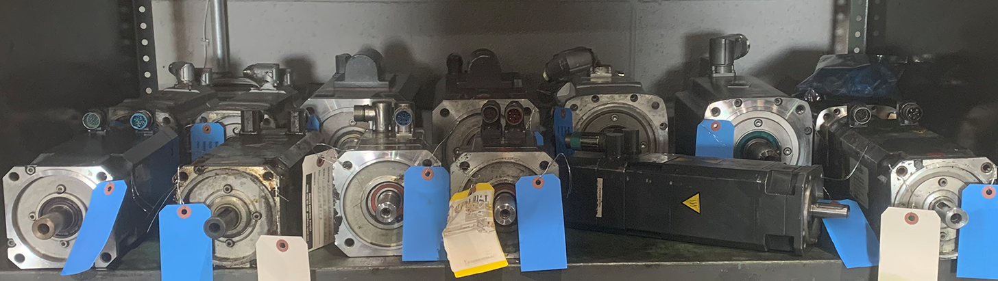 Shelf of blue-tagged servo motors awaiting repair at Apex Industrial Automation’s servo repair laboratory.