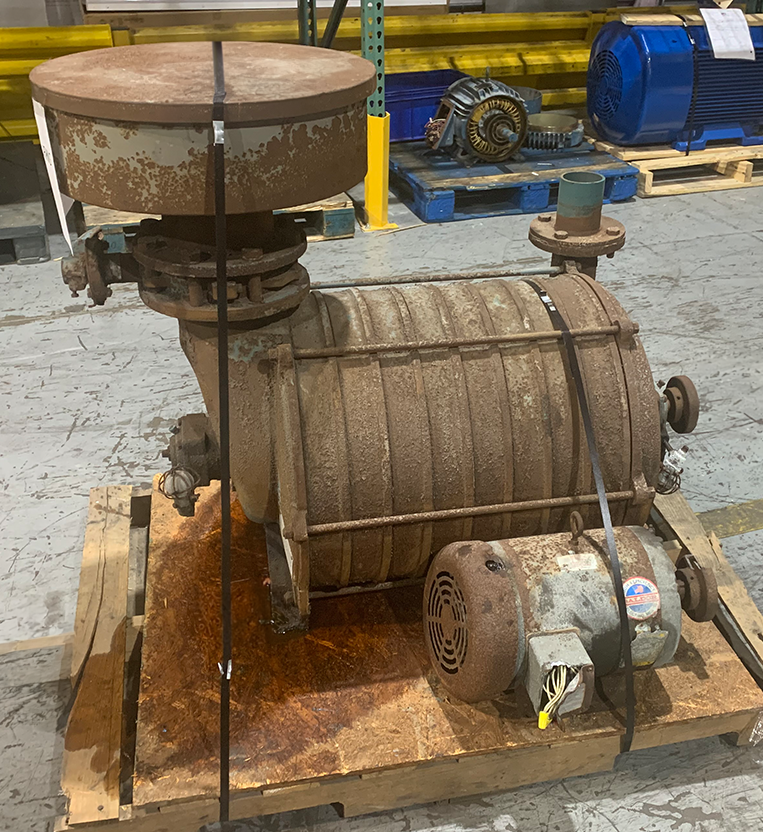 Legacy rusted electric motor with a large pump impeller and pipes along the side awaiting repair at Apex Industrial Automation