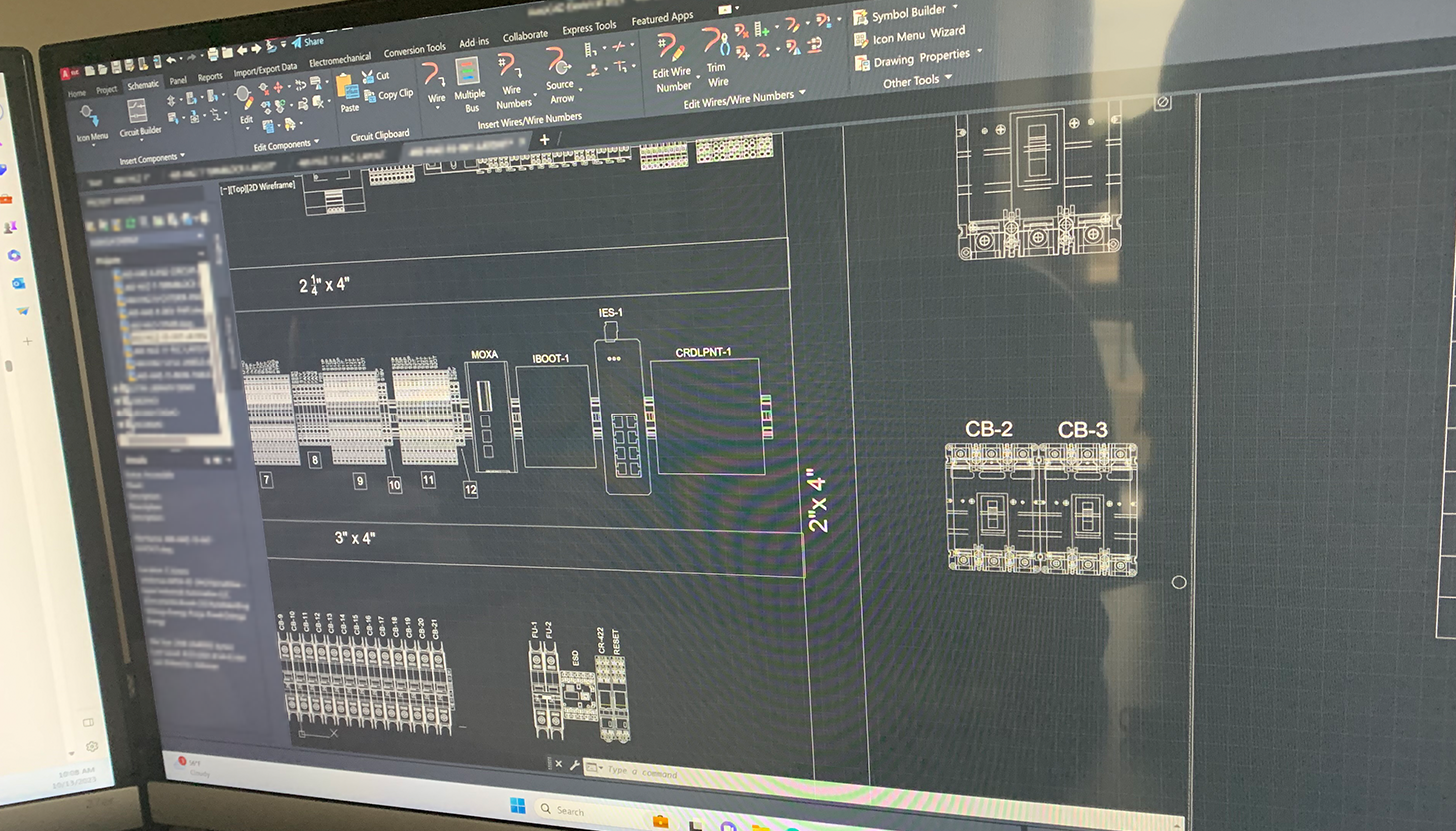 Close-up of a monitor at Apex Industrial Automation showing a control panel design in AutoCAD, highlighting system integration and retrofitting.