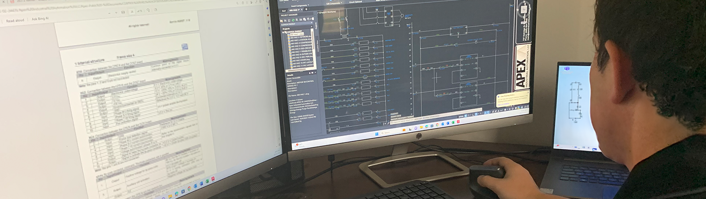 Over-the-shoulder view of a control panel design engineer at Apex Industrial Automation working on a custom control panel design in AutoCAD.